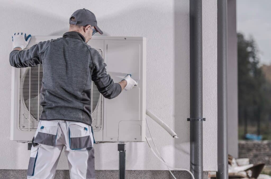 Mann som installerer varmepumpe for noen som ønsker å spare strøm