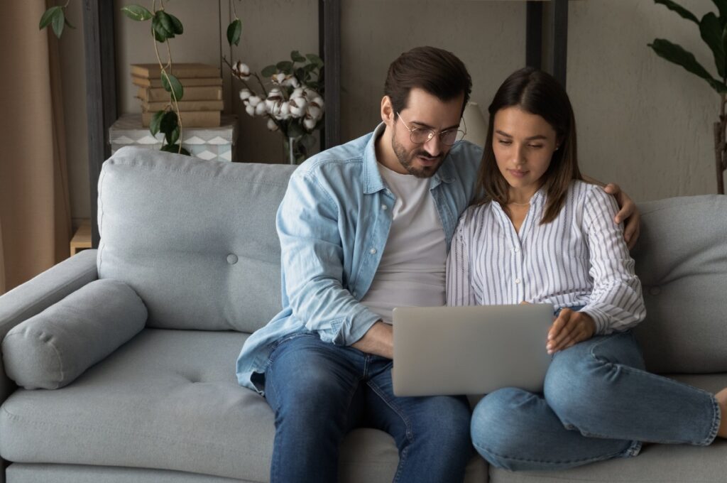 Mann og kvinne i sofa hjemme som undersøker forbrukslån på dagen